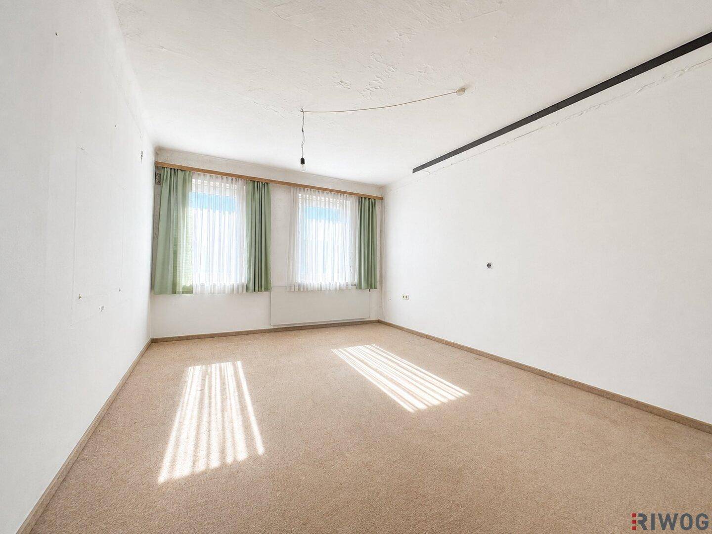 Geräumiges Schlafzimmer mit Teppichboden, zwei Fenstern und viel Tageslicht.