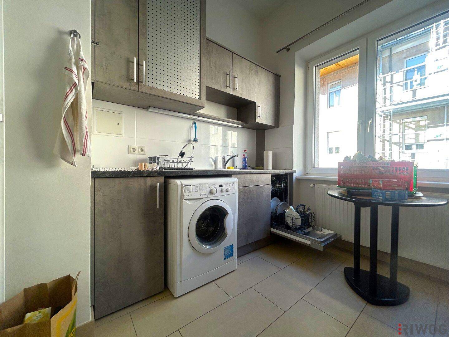 Funktionale Küche mit Waschmaschine, Geschirrspüler und Fenster, ideal für den Alltag.