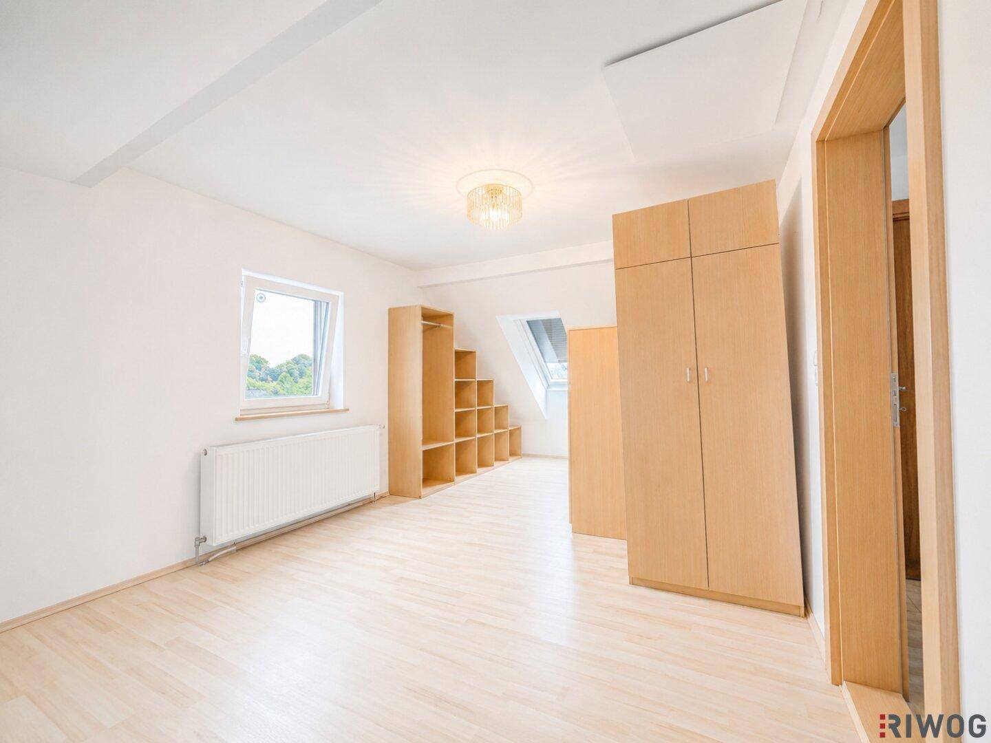 Heller Dachbodenraum mit Holzboden, Dachschrägen, Fenster und praktischen Einbauschränken.