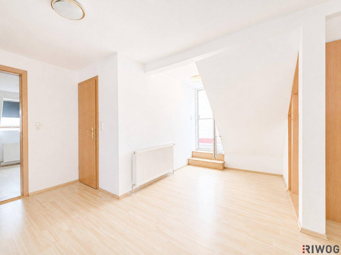 Heller Flur im Dachgeschoss mit Holzboden, Heizkörper und Treppenaufgang zu einem weiteren Bereich.