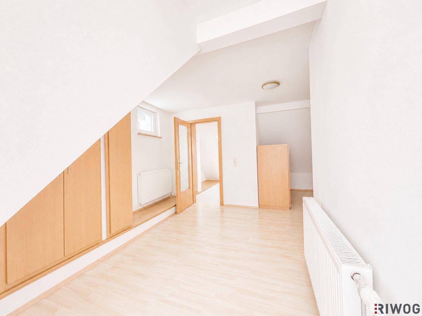 Dachbodenraum mit Holzboden, Dachschrägen und integrierten Schränken entlang der Wand.