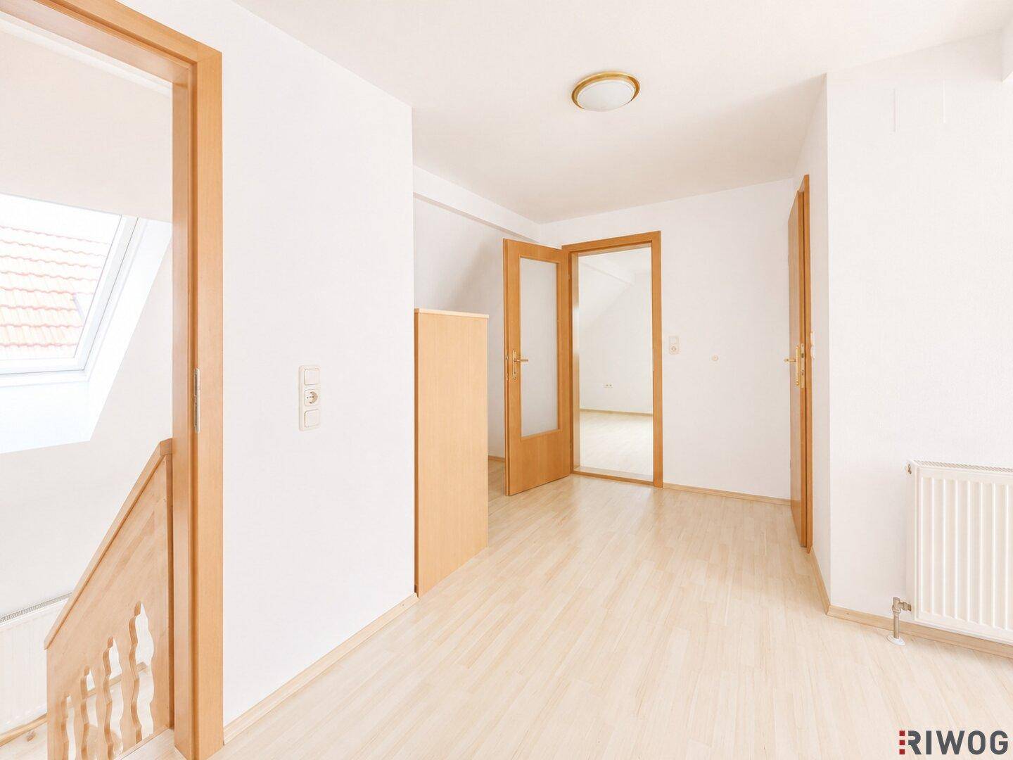 Heller Flur im Dachgeschoss mit Holzboden und mehreren Türen zu angrenzenden Räumen.