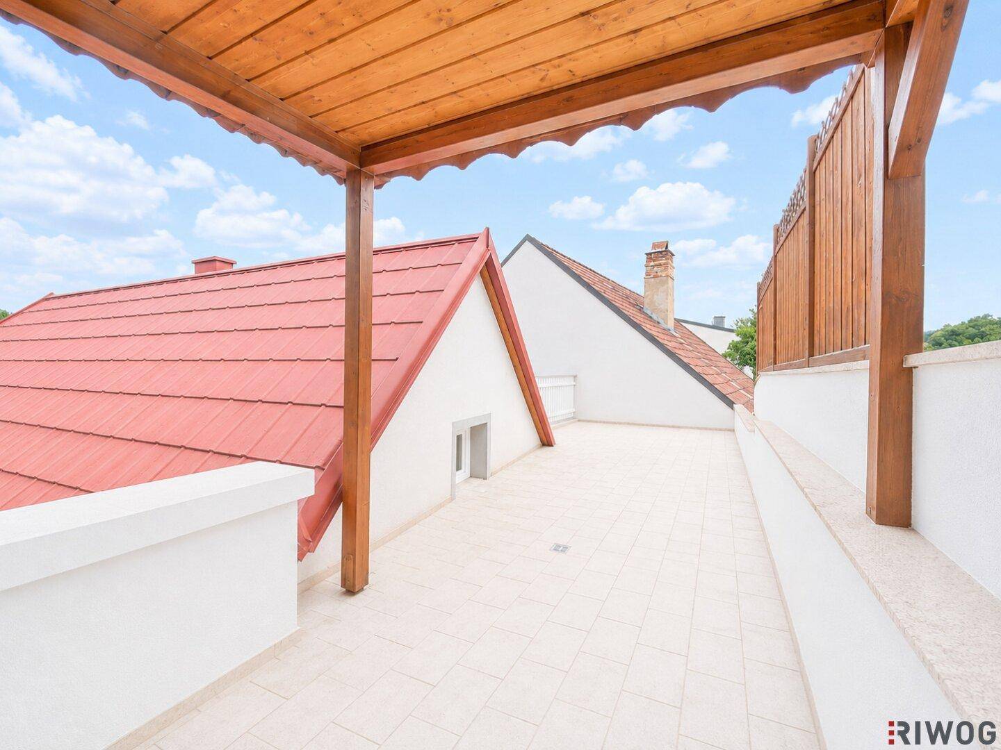 Helle Dachterrasse mit Holzpergola, Fliesenboden und weitem Blick über die Dächer.