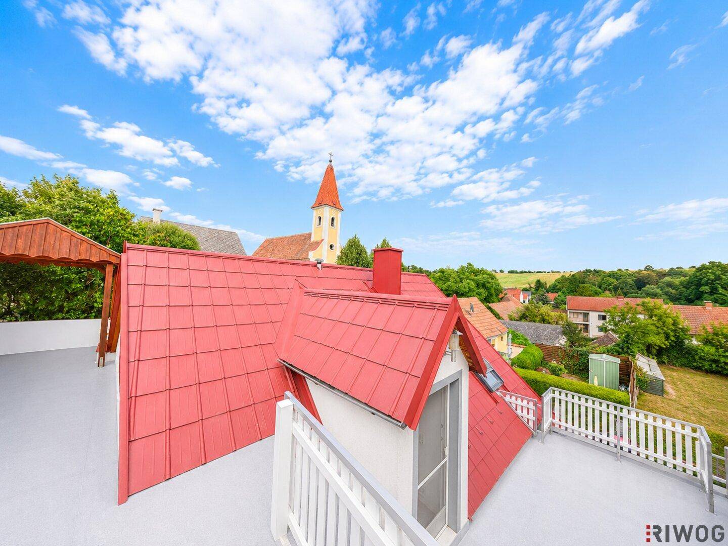 Weitläufige Dachterrasse mit Panoramablick auf die ländliche Umgebung und die Kirchturmspitze.