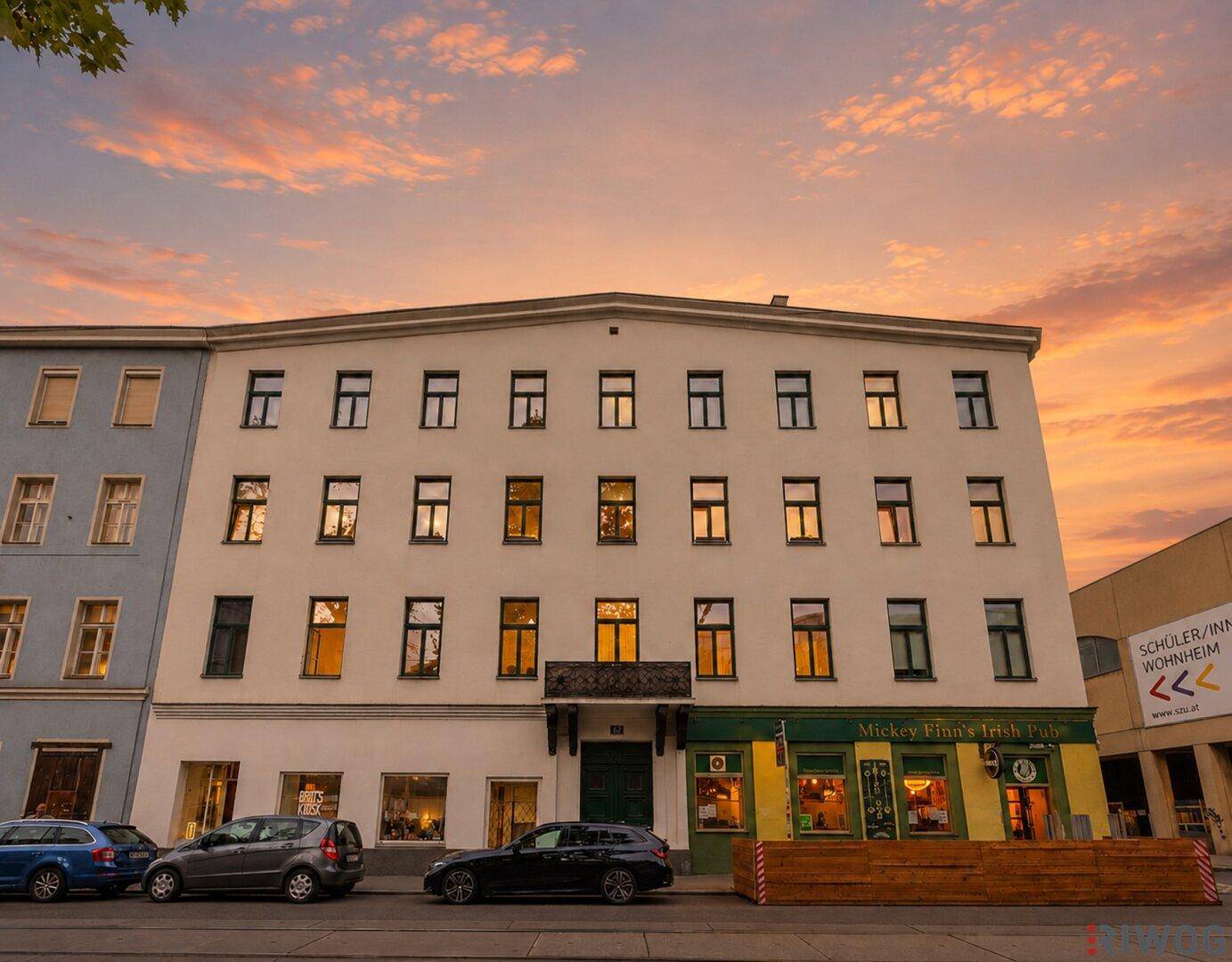 Historisches Gebäude mit vielen Fenstern und einem Pub im Erdgeschoss bei Sonnenuntergang.