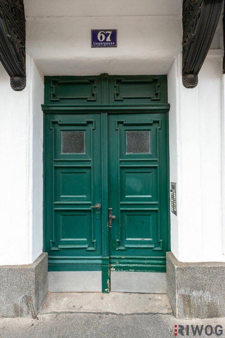 Grüne Eingangstür eines historischen Gebäudes mit Hausnummer 67 und traditionellen Details.