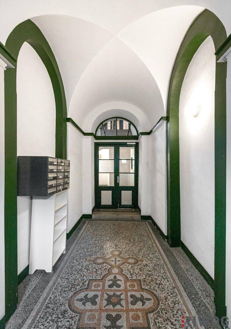Historischer Eingangsbereich mit Gewölbedecke, Mosaikboden und grünen Akzenten.