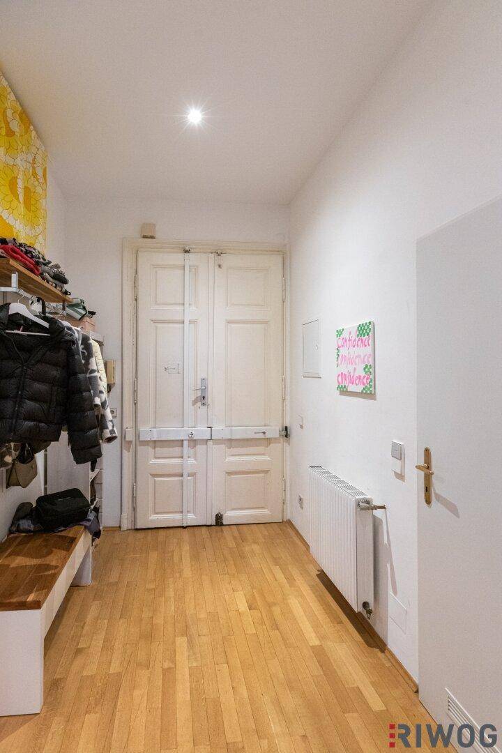 Eingangsbereich mit Holzboden, Garderobe und weiß gestrichenen Wänden.