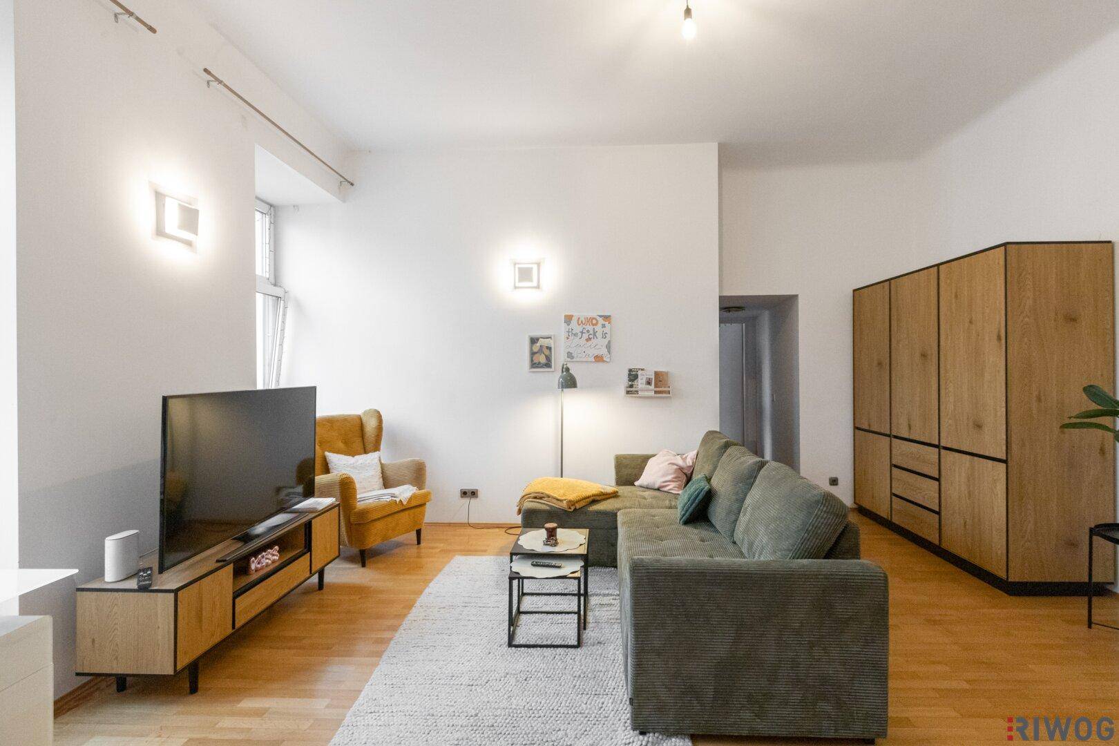 Geräumiges Wohnzimmer mit Holzboden, weiß gestrichenen Wänden und moderner Einrichtung.