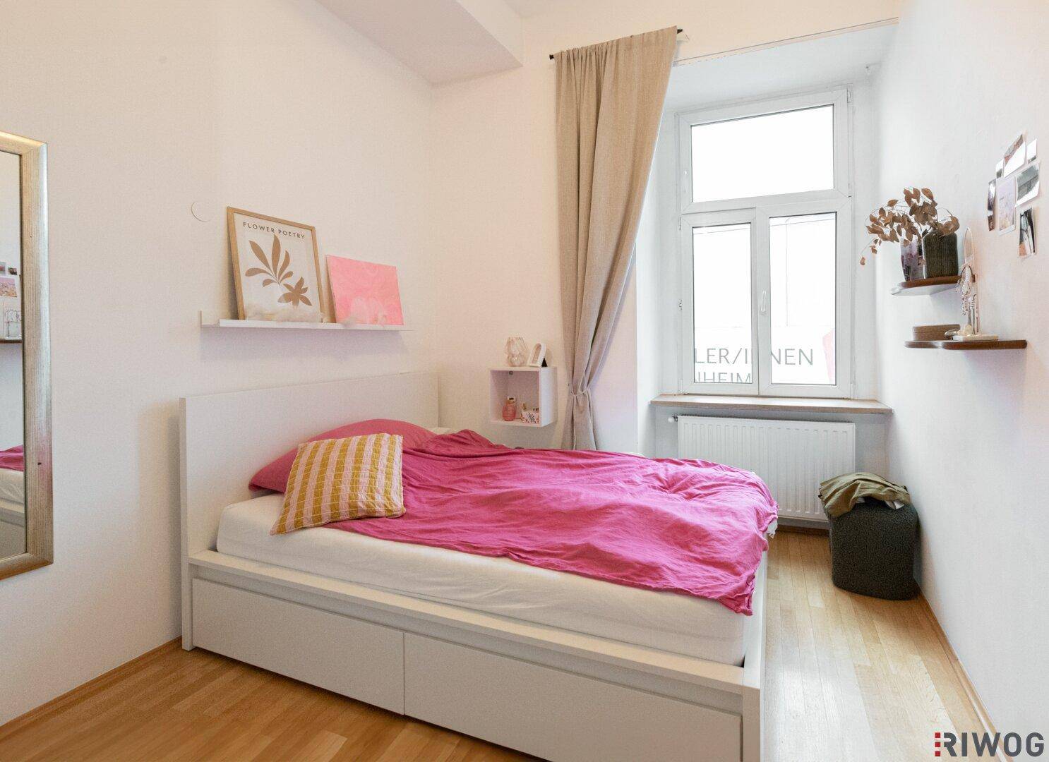 Gemütliches Schlafzimmer mit Holzboden, Einzelbett und Fenster mit Vorhang.