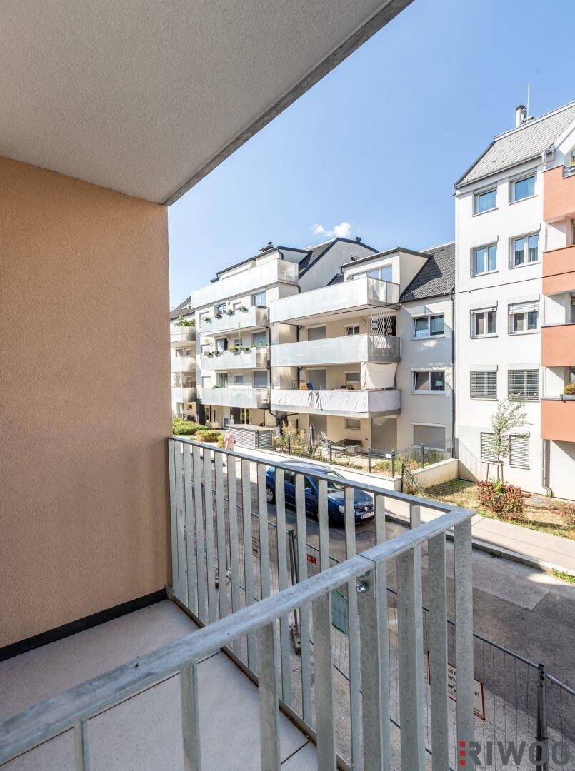 Blick von einem Balkon auf die umliegenden Wohngebäude und die ruhige Straße.