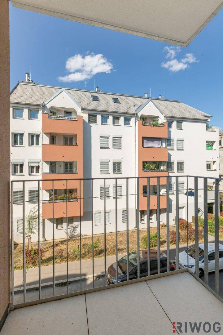 Aussicht von einem Balkon auf die moderne Fassade eines gegenüberliegenden Wohngebäudes.