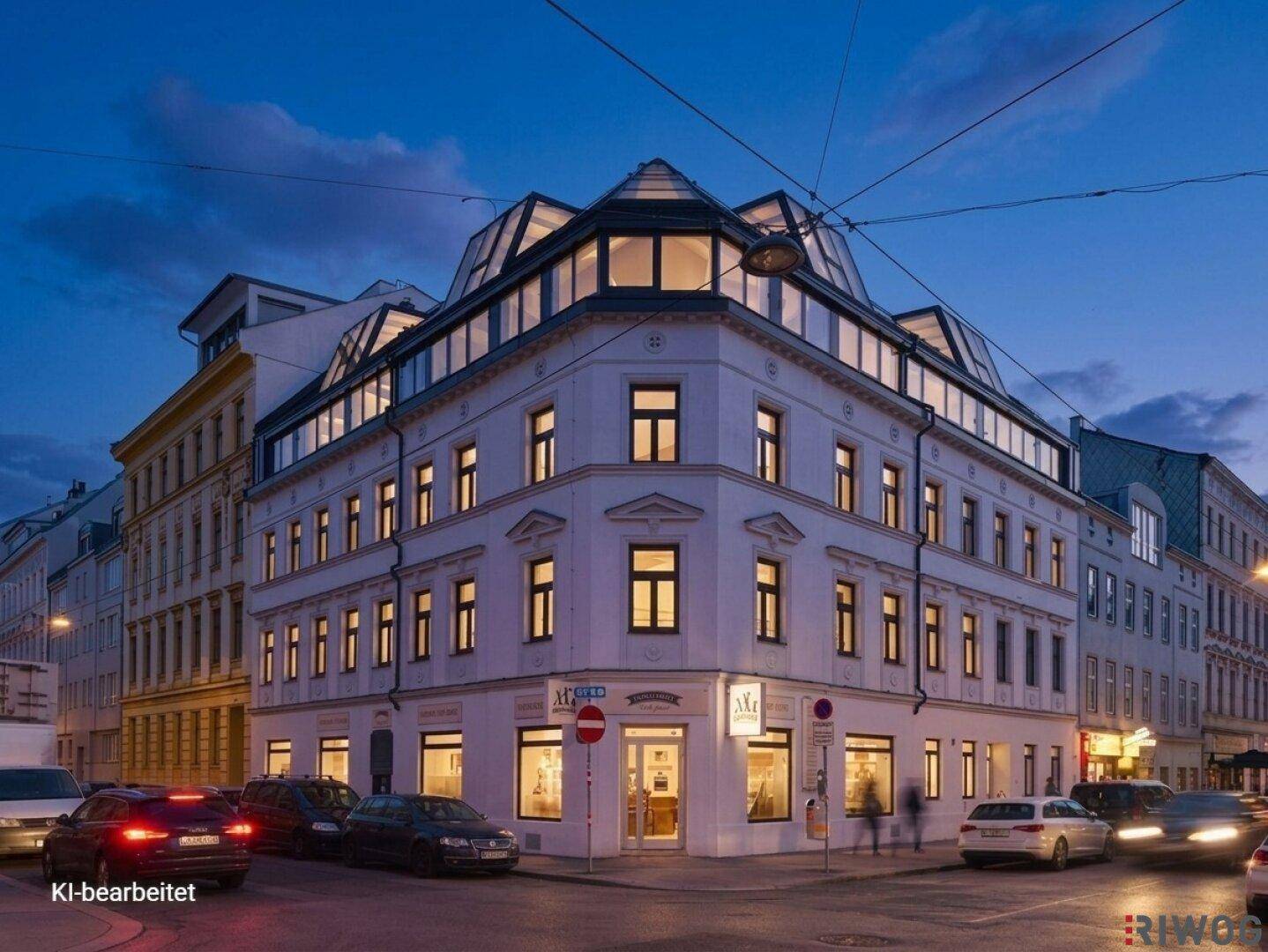 Modernisiertes Eckgebäude mit großen Fenstern und Dachausbau in der Abenddämmerung.
