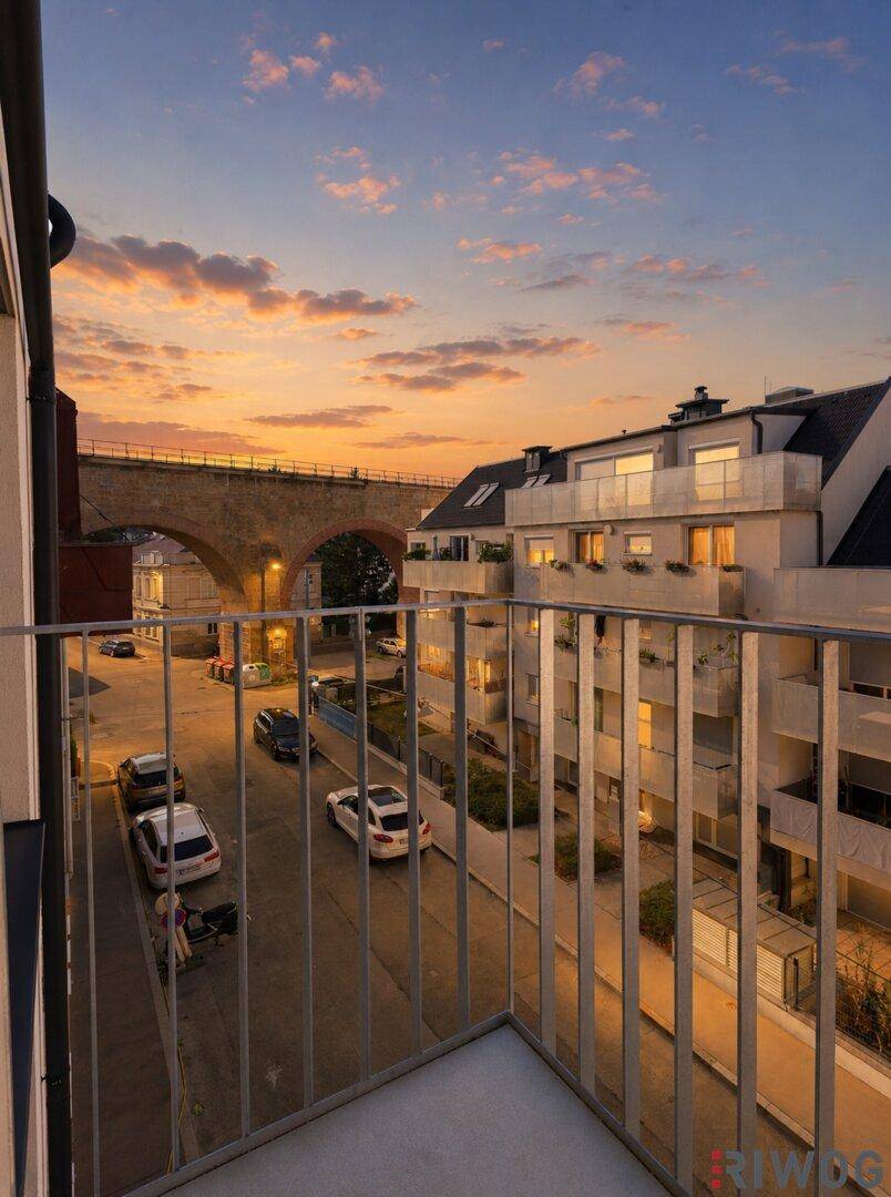 Balkon mit Blick auf die Straße und eine historische Brücke bei Sonnenuntergang.