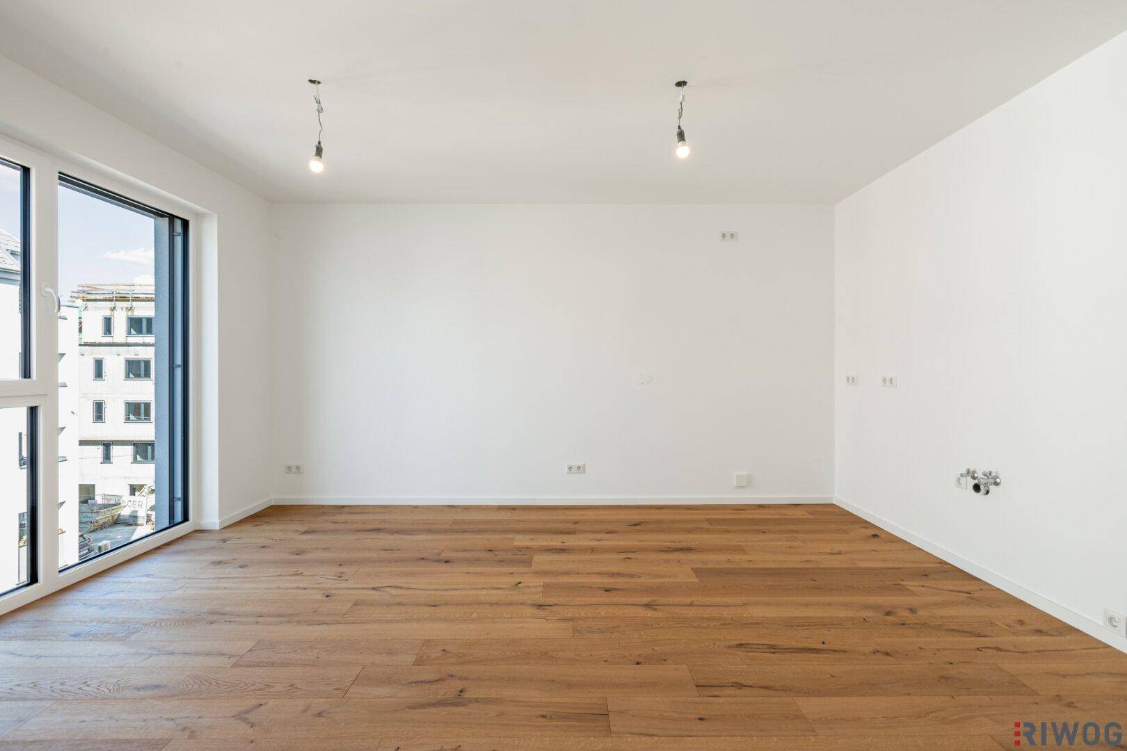 Geräumiges, leeres Zimmer mit großen Fenstern und hochwertigem Holzboden, ideal für individuelle Gestaltung.