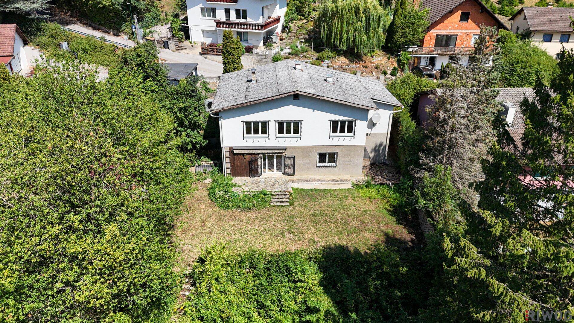 Luftaufnahme eines Hauses mit großem Gartenbereich, umgeben von Bäumen und Natur.