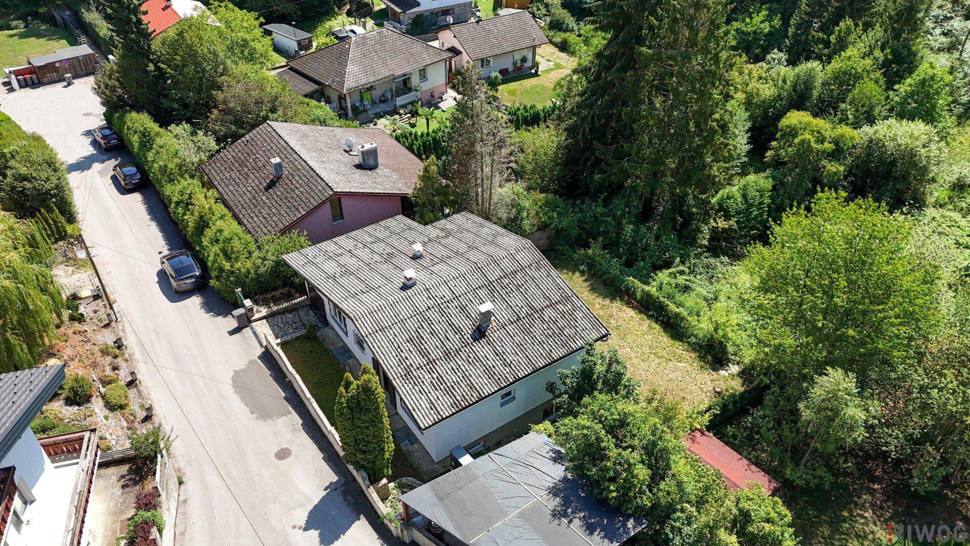Luftaufnahme eines Hauses mit Garten und angrenzender Straße in ländlicher Umgebung.