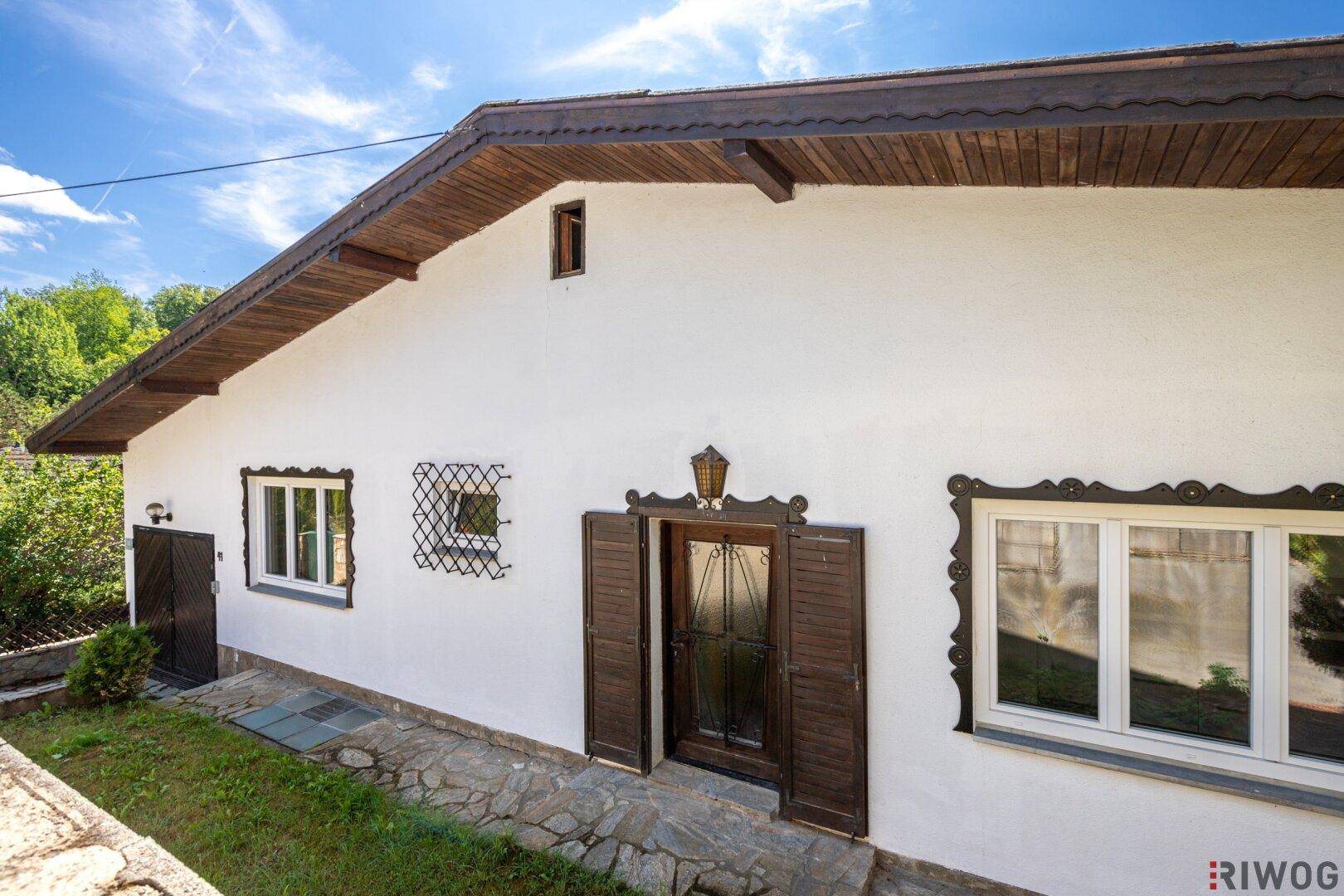Eingangsbereich des Hauses mit Holztür und traditionellen Fenstergittern.