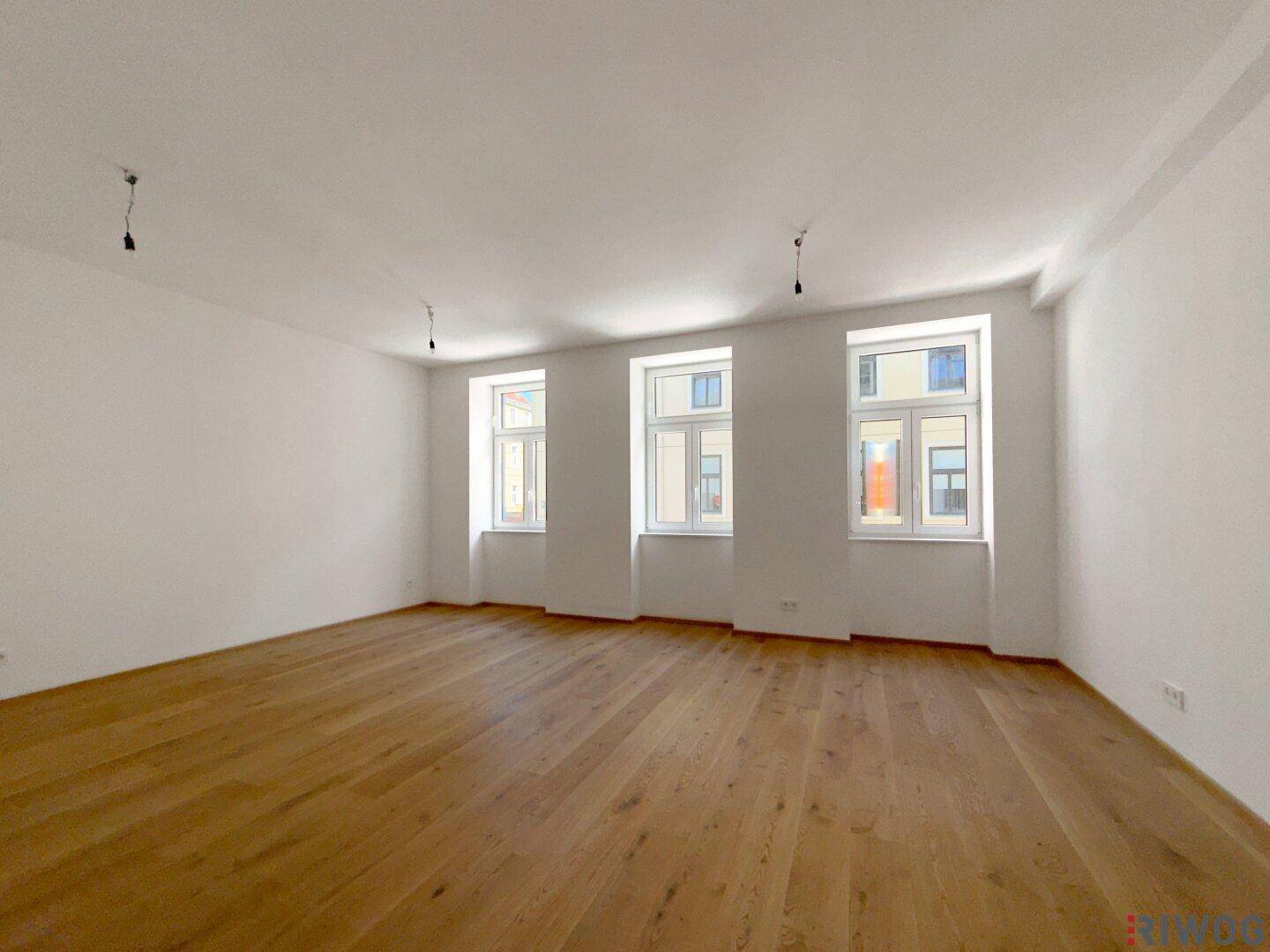 Heller, leerer Wohnraum mit hohen Decken und neuem Holzfußboden, ideal für individuelle Gestaltung.