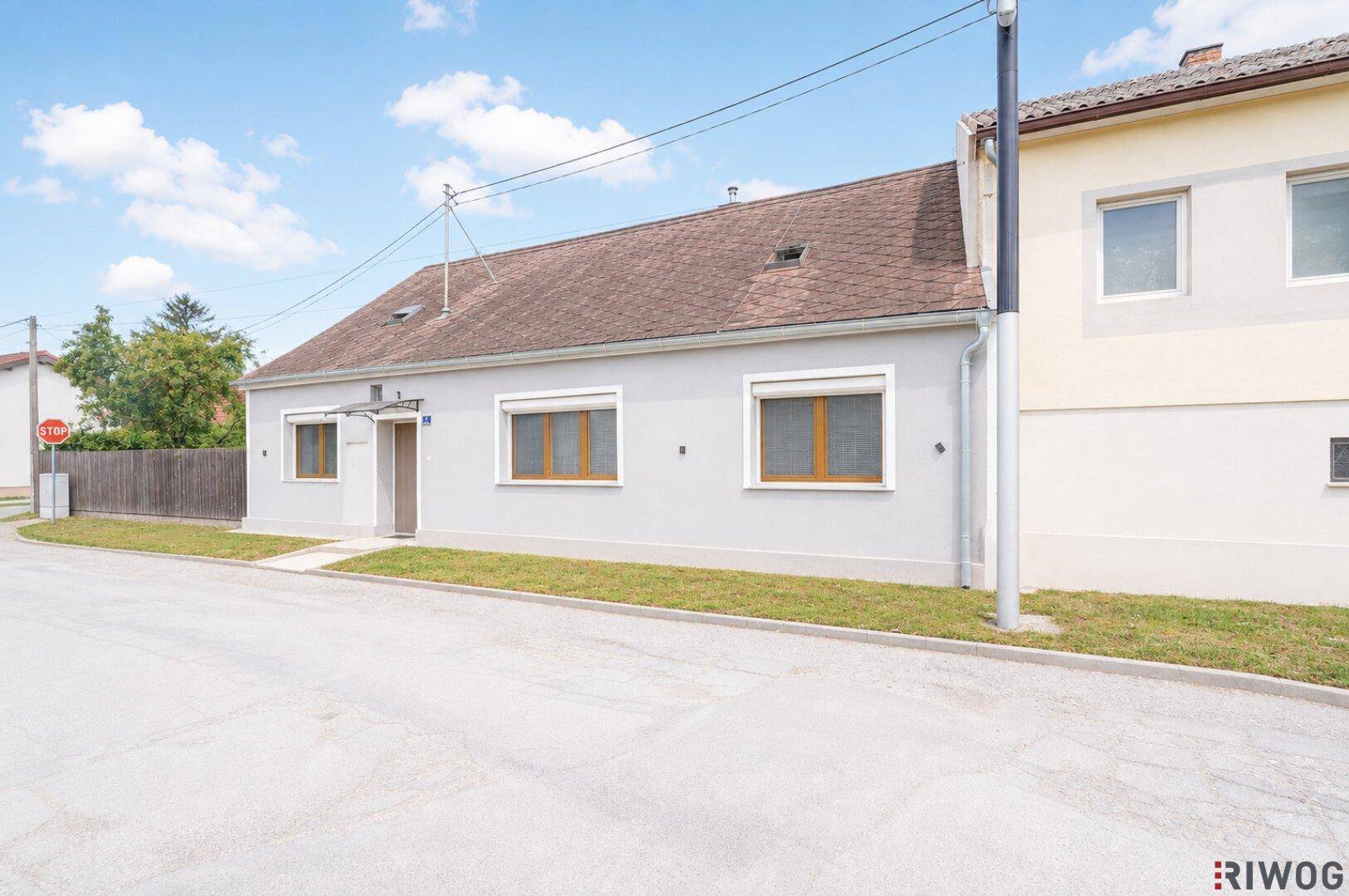 Ansicht des Einfamilienhauses von der Straße mit gepflegtem Vorgarten und Rollläden an den Fenstern.