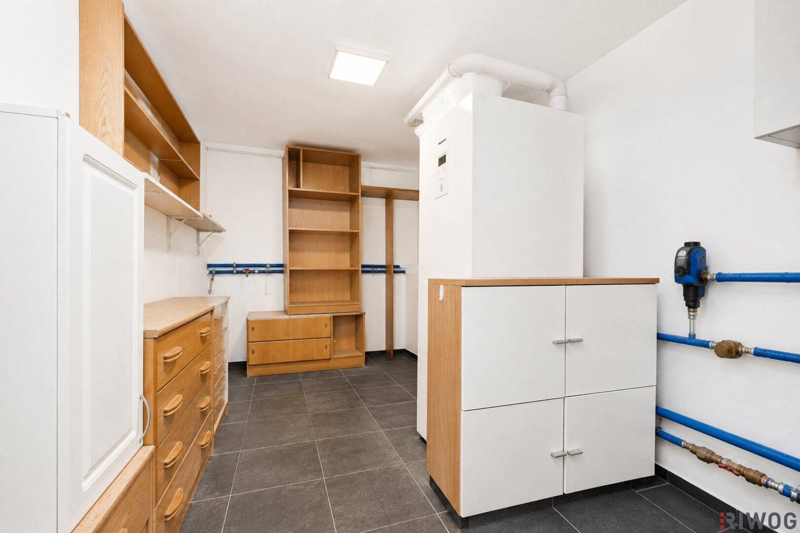 Geräumiger Hauswirtschaftsraum mit Regalen, Schränken und Heizungsanlage.