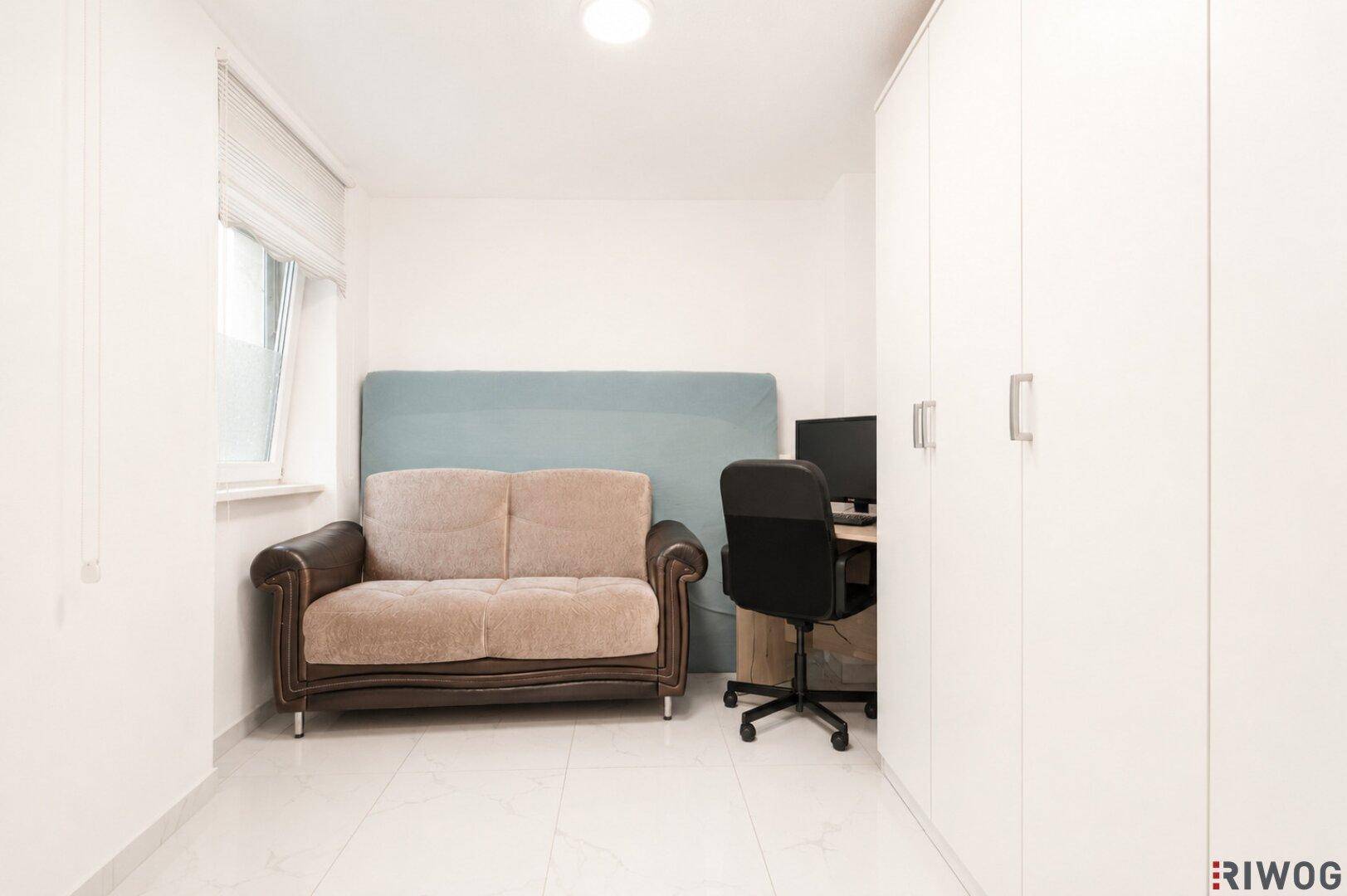 Helles Zimmer mit Sofa, Schreibtisch und Einbauschrank, ideal als Büro oder Gästezimmer.