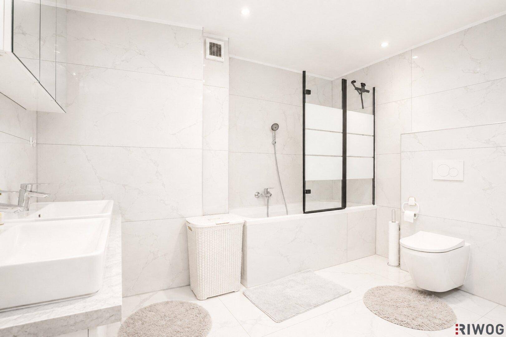 Modernes Badezimmer mit Badewanne, Dusche, Doppelwaschbecken und weißen Fliesen.