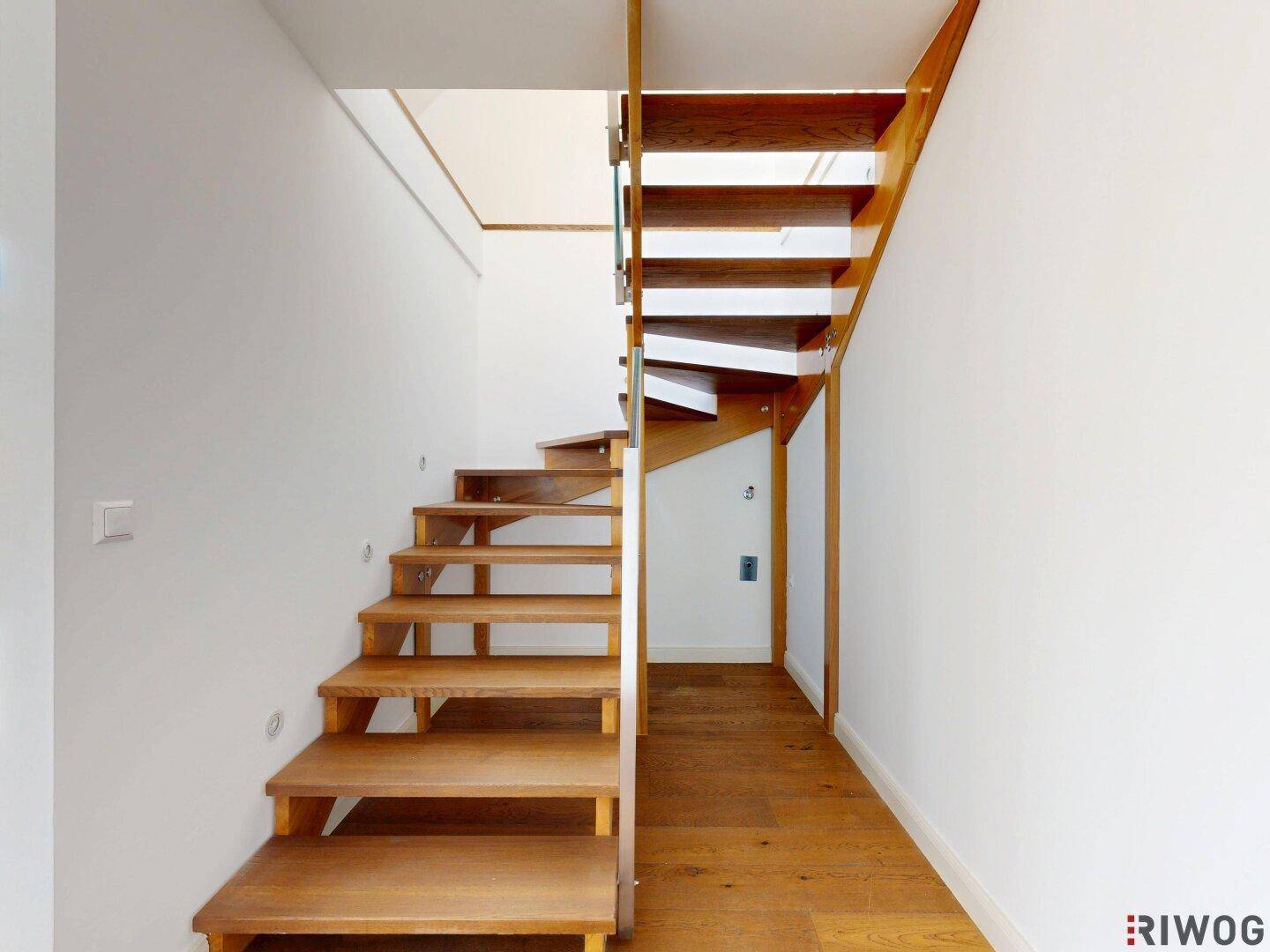 Elegante Holztreppe mit offenem Design, die die verschiedenen Ebenen der Wohnung verbindet.