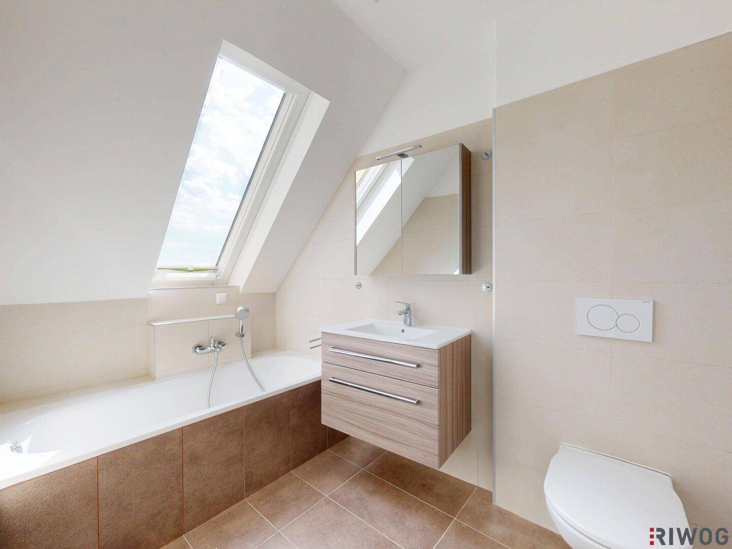 Modernes Badezimmer mit Badewanne, Waschtisch und Dachfenster für viel Tageslicht.