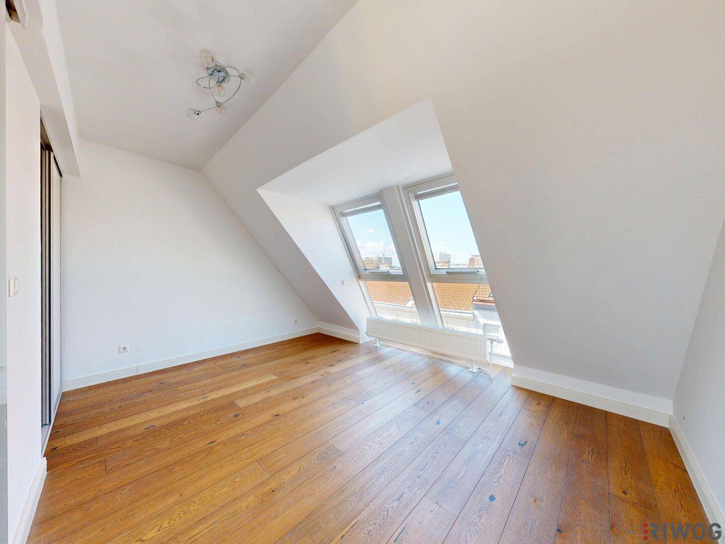 Geräumiges Schlafzimmer mit Holzboden, Dachschrägen und hellen Dachfenstern.