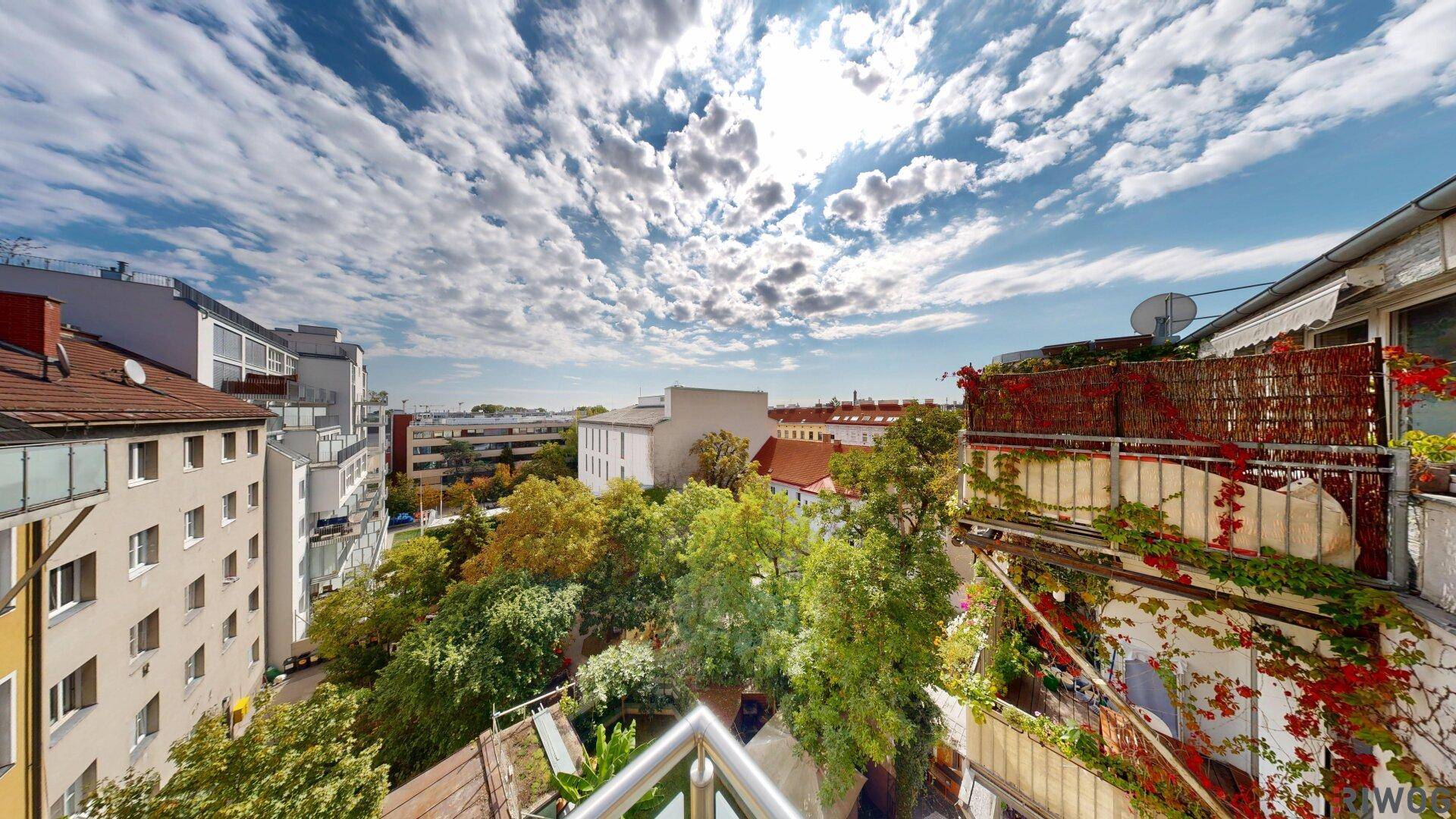 Weitläufiger Blick von einem Balkon über grüne Bäume und die umliegende Stadtlandschaft.