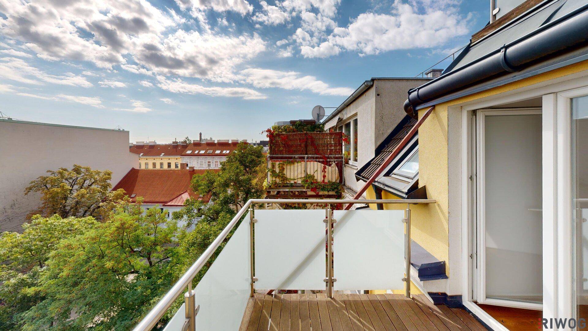 Balkon mit Holzbelag und Glasgeländer, bietet einen schönen Blick auf die Umgebung.
