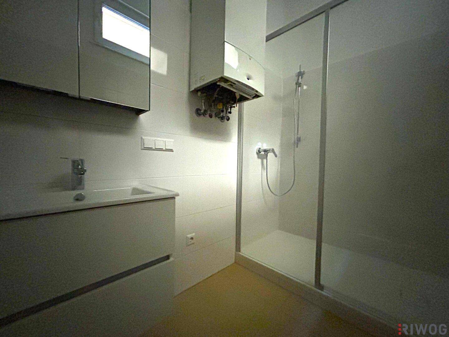 Modernes Badezimmer mit weiß gefliesten Wänden, Dusche und Einzelwaschbecken, inklusive Warmwasserbereiter.