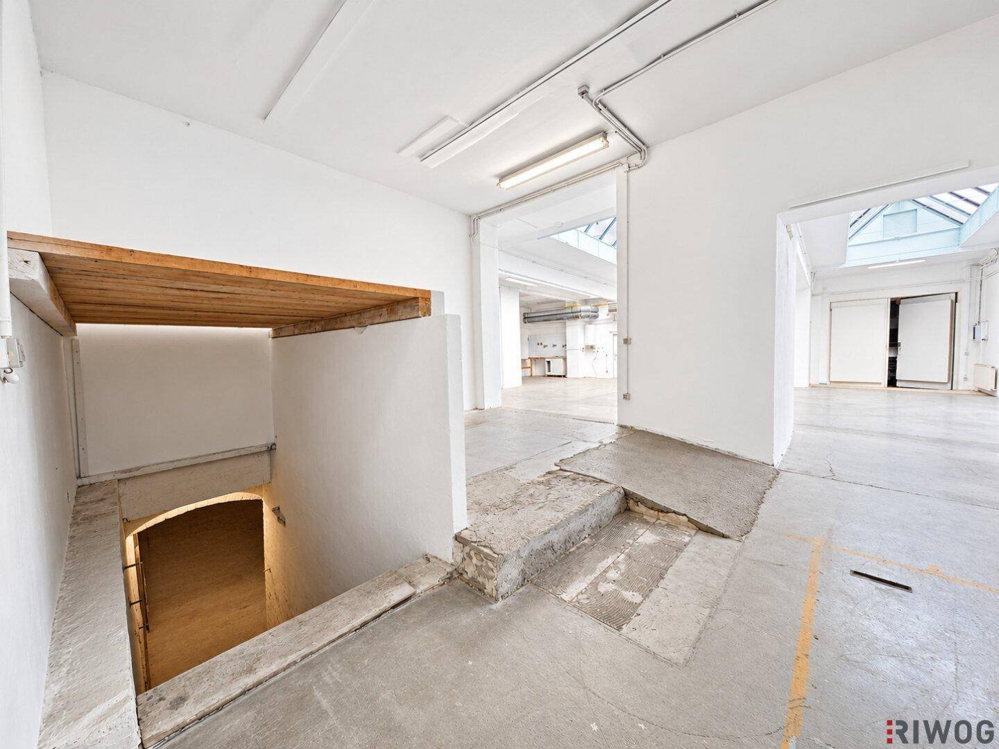 Geräumiger Innenbereich mit Treppe, Rampe und Zugang zu weiteren offenen Räumen, hell beleuchtet.