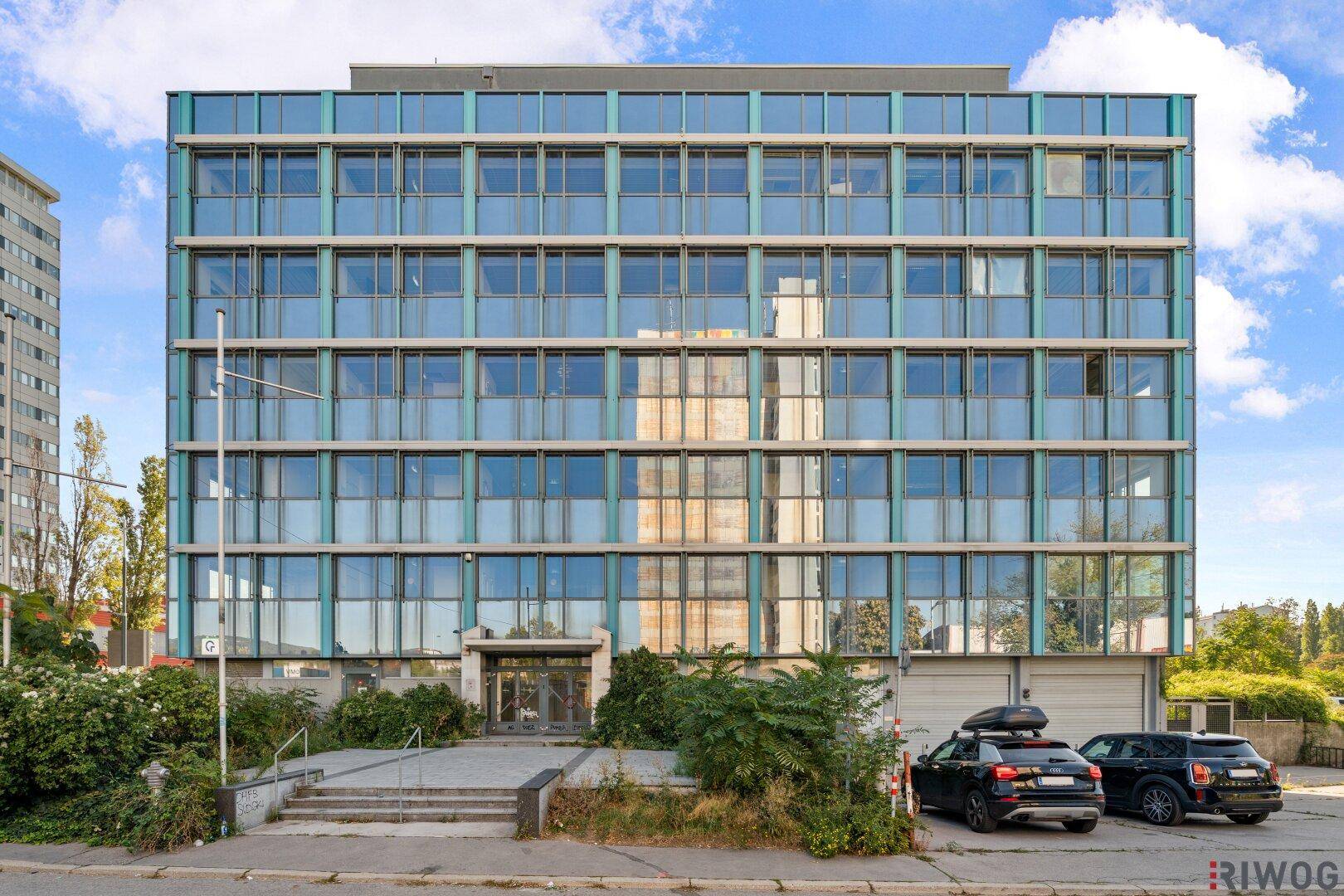 Vorderansicht eines modernen Bürogebäudes mit Glasfassade und Eingangsbereich.