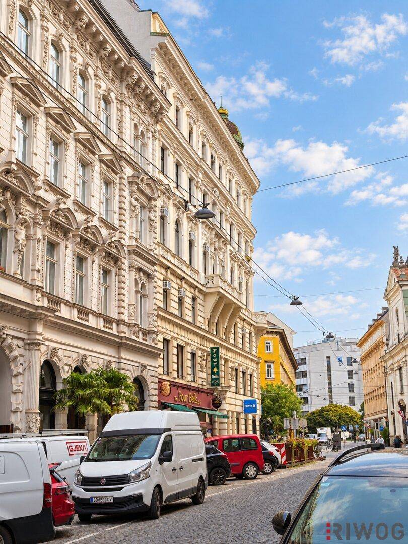 Historisches Gebäude mit reich verzierten Fassaden und Geschäften im Erdgeschoss.
