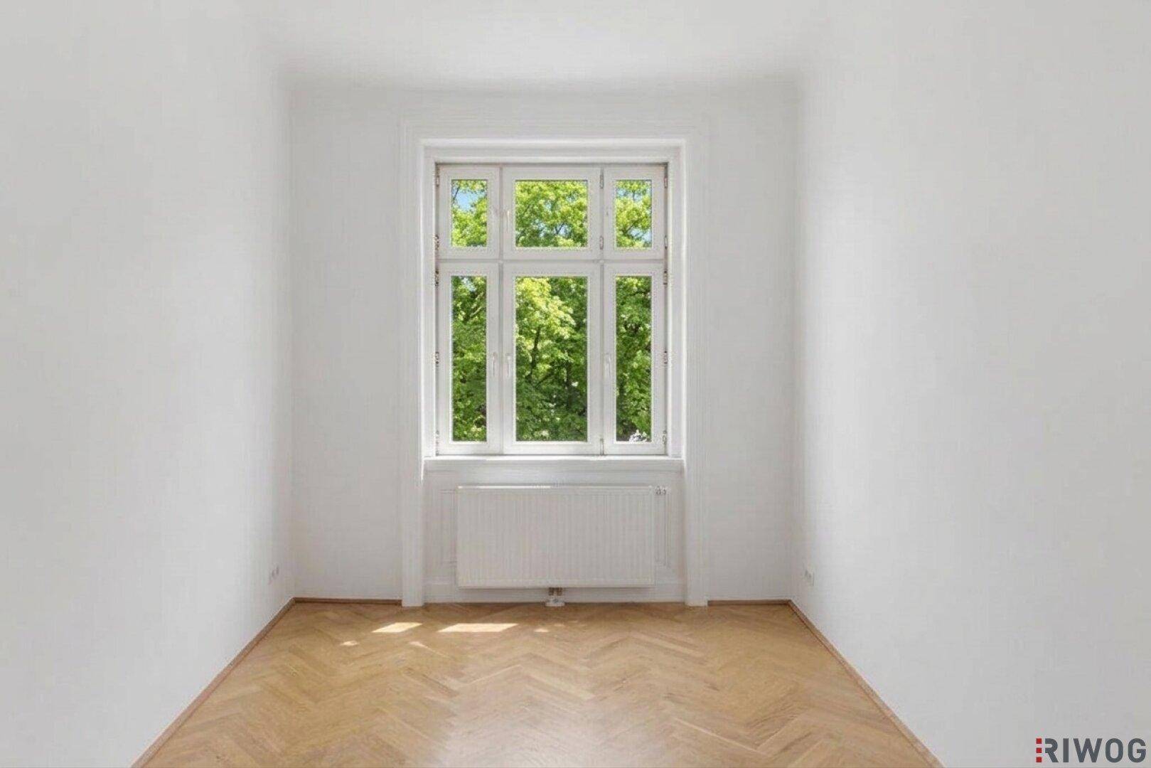 Heller Raum mit einem großen Fenster, das viel Grün und Tageslicht bietet.