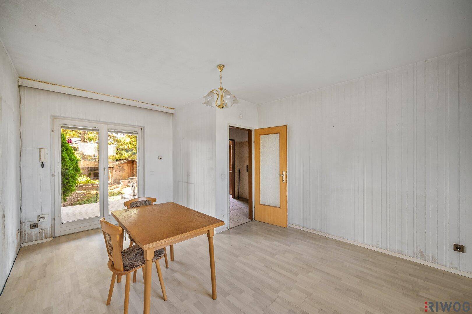 Wohn- und Essbereich mit Laminatboden, Esstisch und Zugang zum Garten.