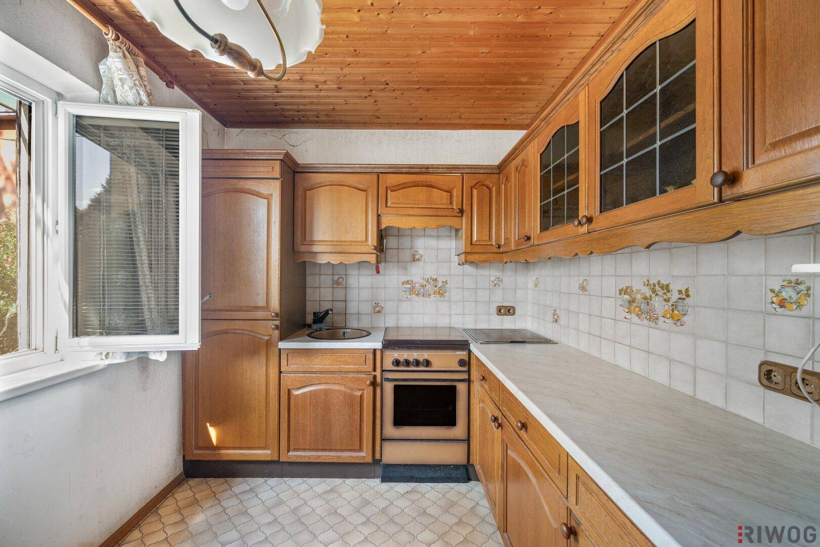 Traditionelle Küche mit Holzschränken, gefliestem Spritzschutz und Holzdecke.