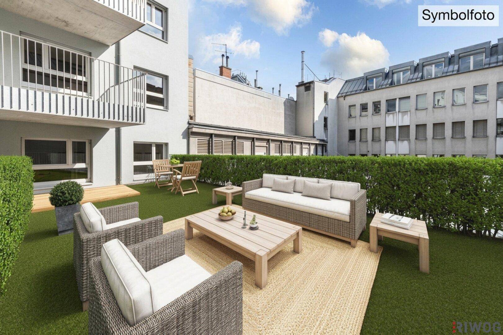 Moderne Terrasse mit Kunstrasen, Hecke und bequemen Outdoor-Sitzmöbeln vor einem Neubau.