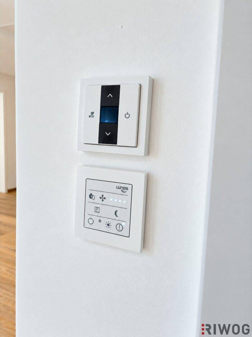 Moderne Bedienelemente für Heizung und Lüftung an einer weißen Wand installiert.