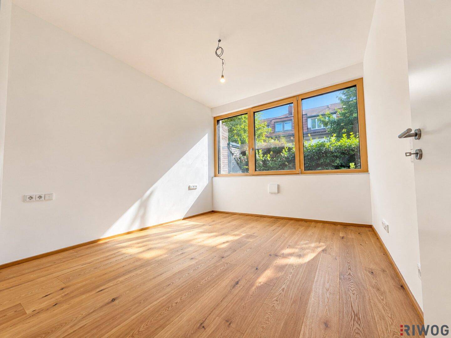 Helles Schlafzimmer mit Parkettboden und Fenstern, die viel Sonnenlicht in den Raum lassen.
