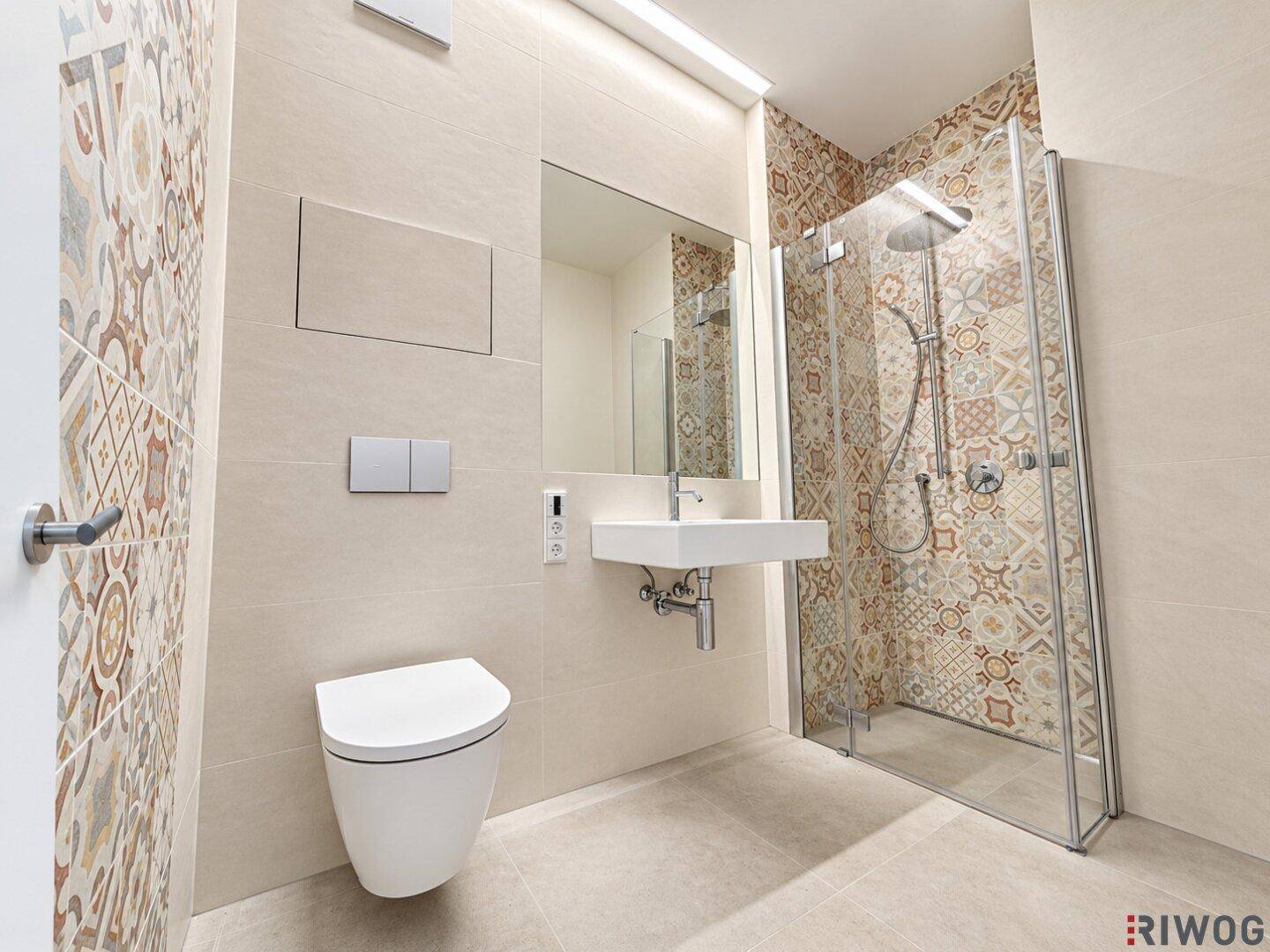 Modernes Badezimmer mit Duschkabine, Wand-WC und dekorativen Fliesen an der Duschwand.