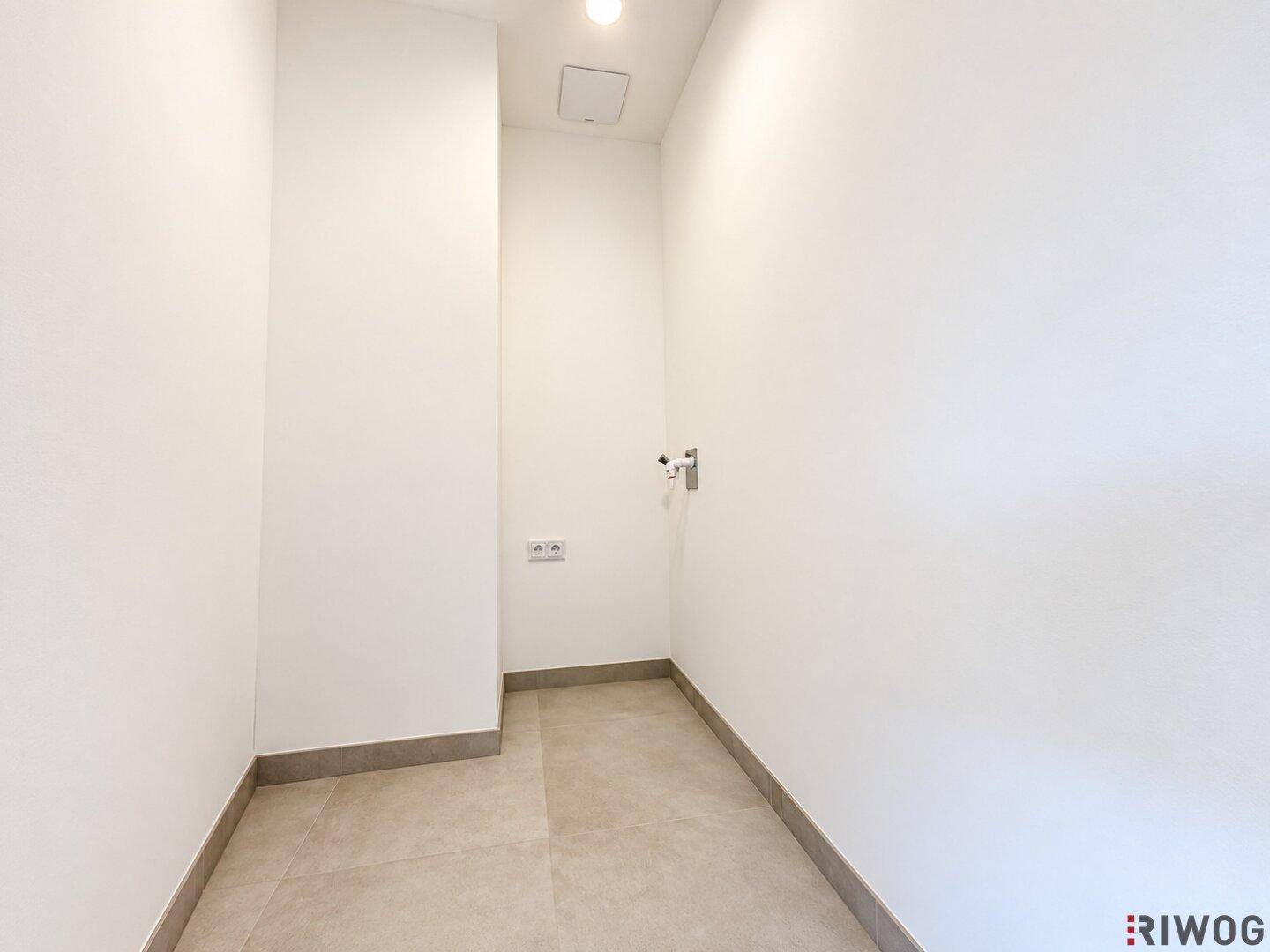 Kleiner Hauswirtschaftsraum mit Fliesenboden und Anschlüssen für Waschmaschine oder Trockner.