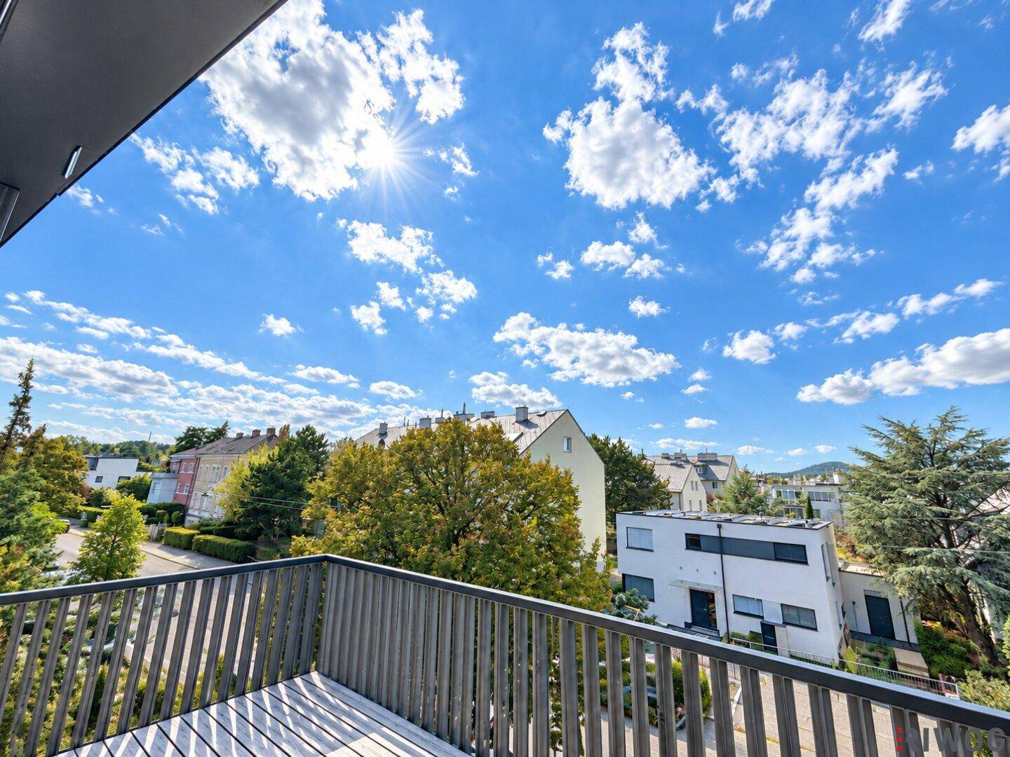 Weitblick von der Terrasse über eine grüne Wohngegend mit vielen Bäumen und Häusern.