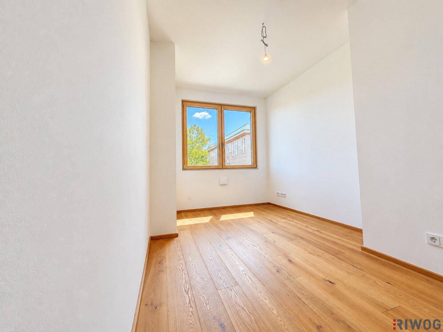 Freundliches Zimmer mit Holzboden und Fenster, ideal als Schlaf- oder Arbeitszimmer nutzbar.