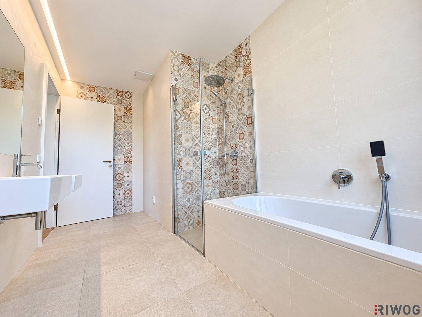 Modernes Badezimmer mit Badewanne, Duschkabine, Einzelwaschbecken und dekorativen Fliesen.