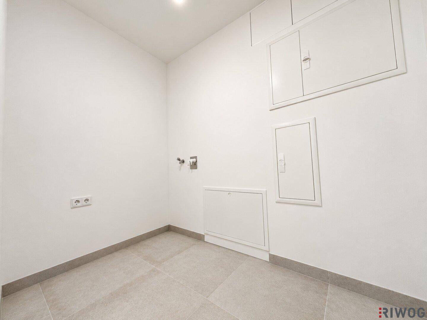 Funktionaler Hauswirtschaftsraum mit Fliesenboden und Anschlüssen für Waschmaschine oder Trockner.
