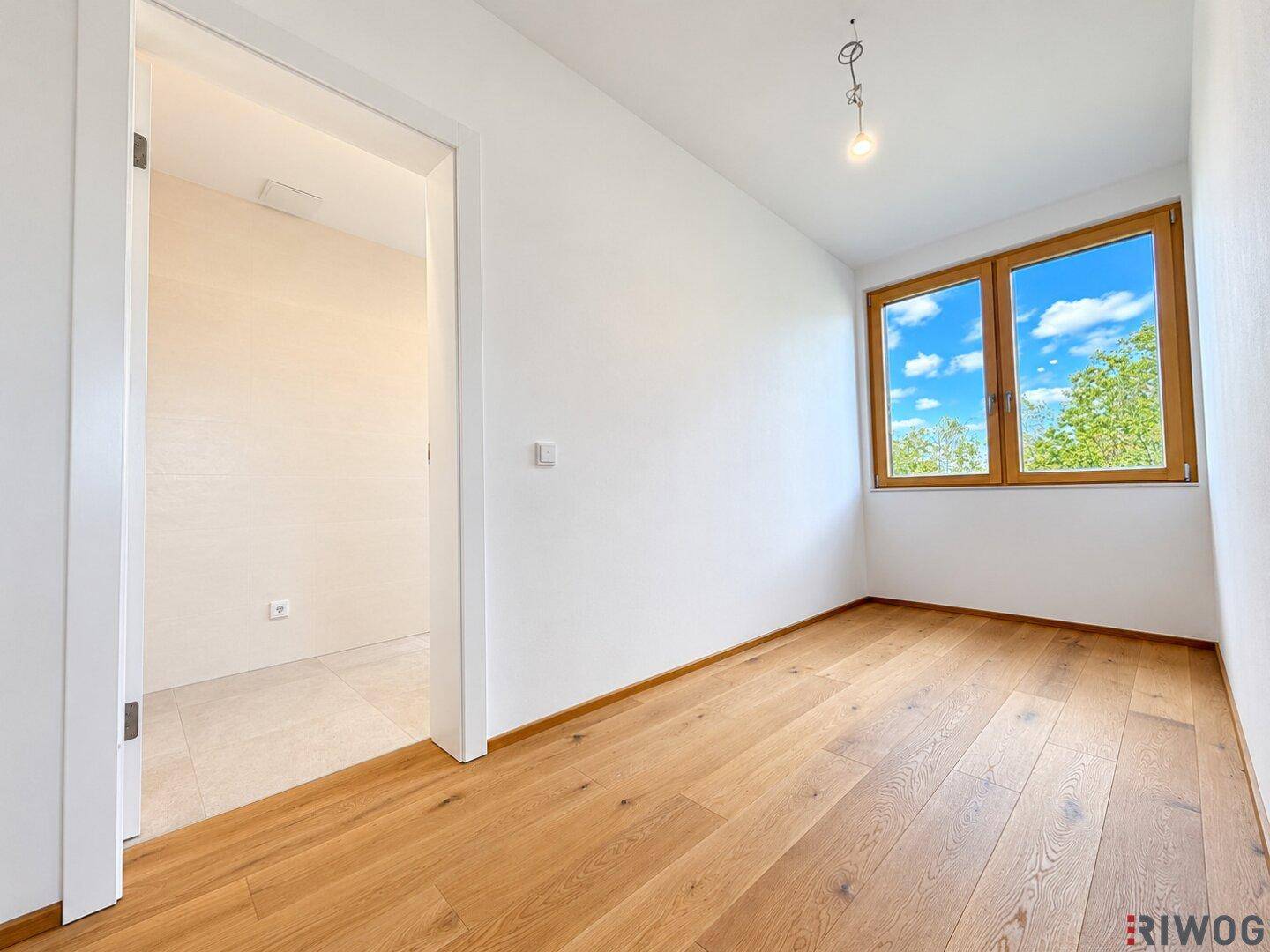 Helles Zimmer mit Holzboden und Fenster, das sich ideal als Schlaf- oder Arbeitszimmer eignet.