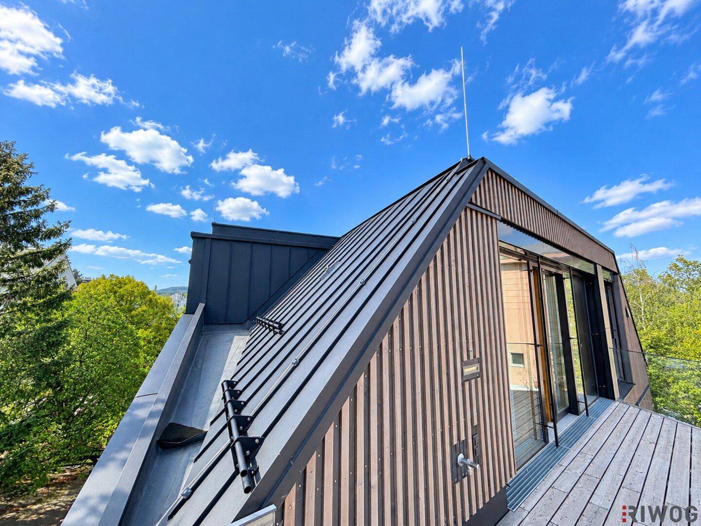 Moderne Dachkonstruktion mit dunklem Metall und Holzverkleidung unter einem strahlend blauen Himmel.